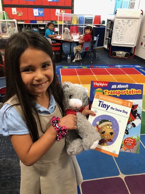 little girl with reading buddy and books